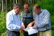 Förster und zwei Waldbesitzer unterhalten sich im Wald
