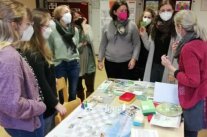Frauen stehen um einen Tisch mit Unterrichtsmaterial