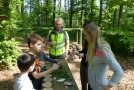 Kinder stehen vor einem Tisch an einem Waldspiel.