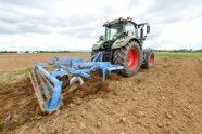 Schlepper bearbeitet mit Grubber ein Feld