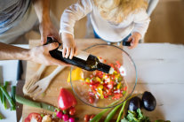 Kleinkind schüttet Öl in eine Salatschüssel